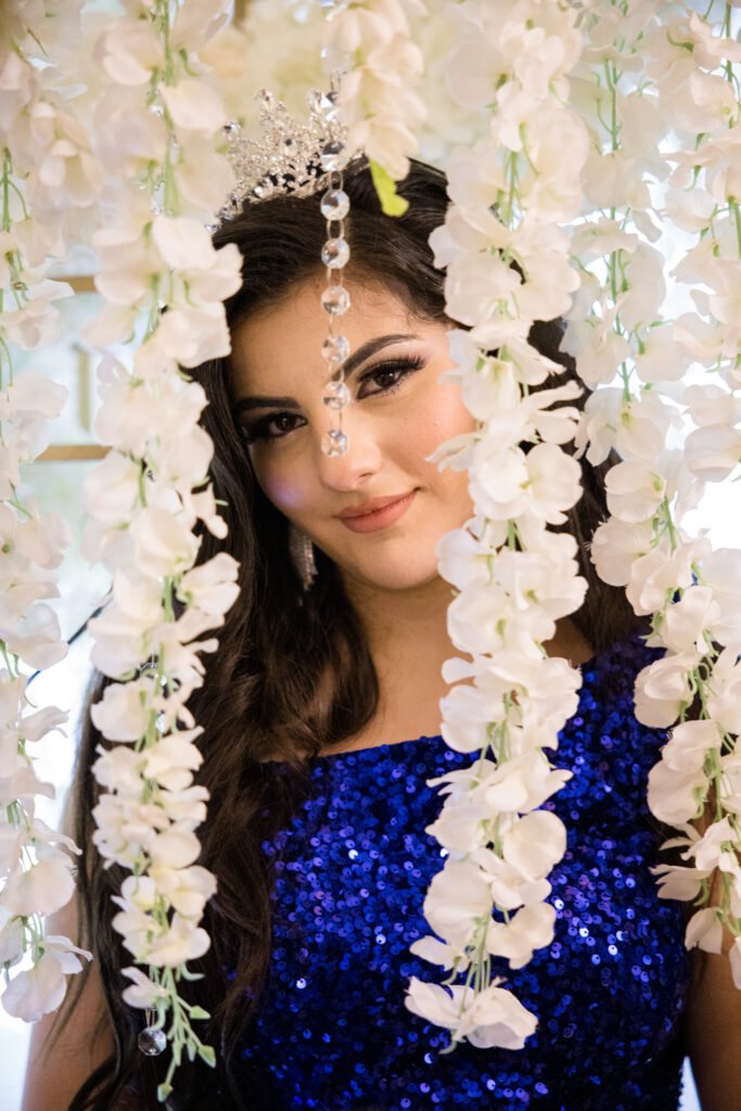 Sweet 16 celebrant beside a white orchid floral wall