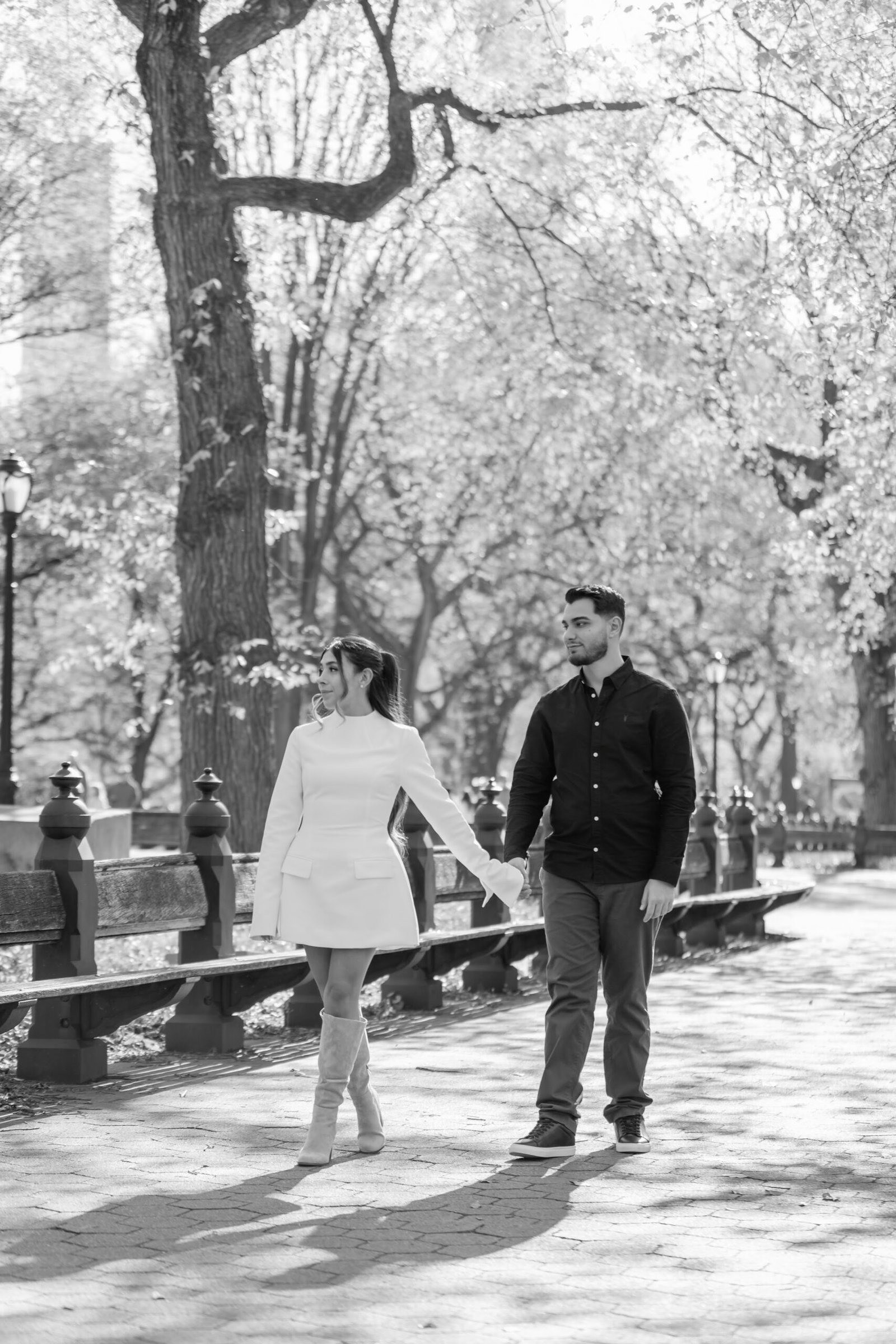 Black and white photograph of the couple walking together through the park
