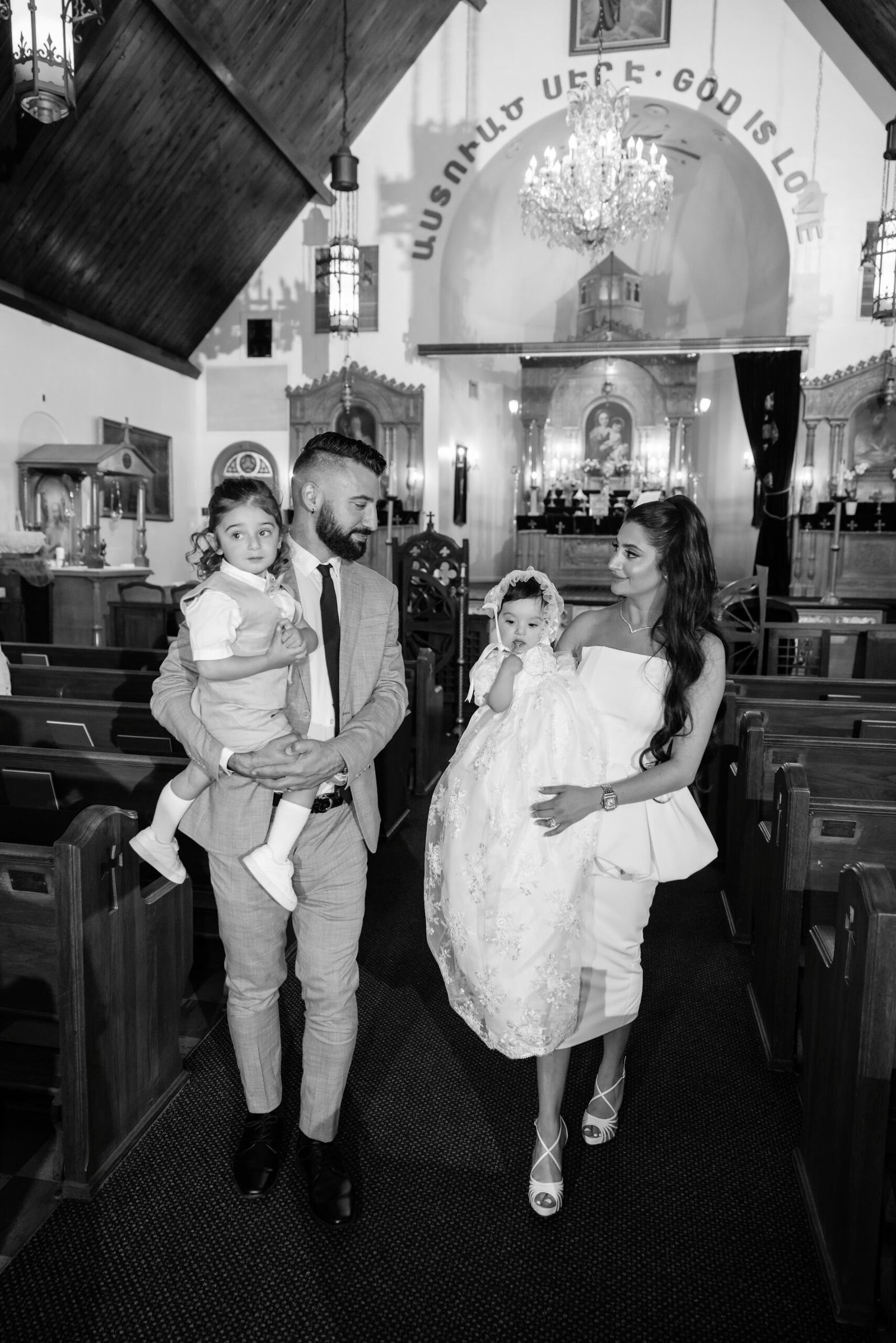 Black and white family photograph with the baby in a christening gown