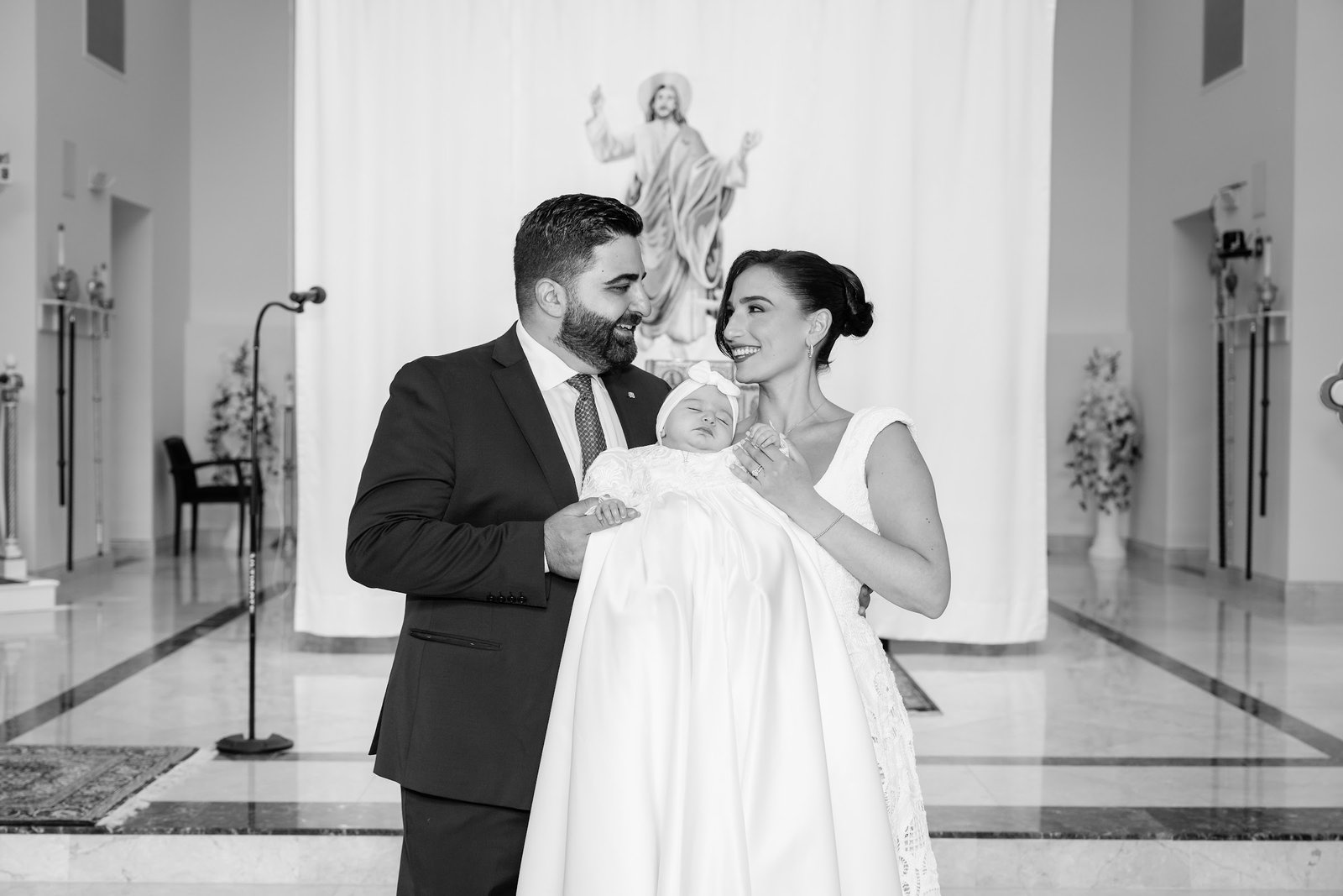 Black and white photograph of parents kissing their baby