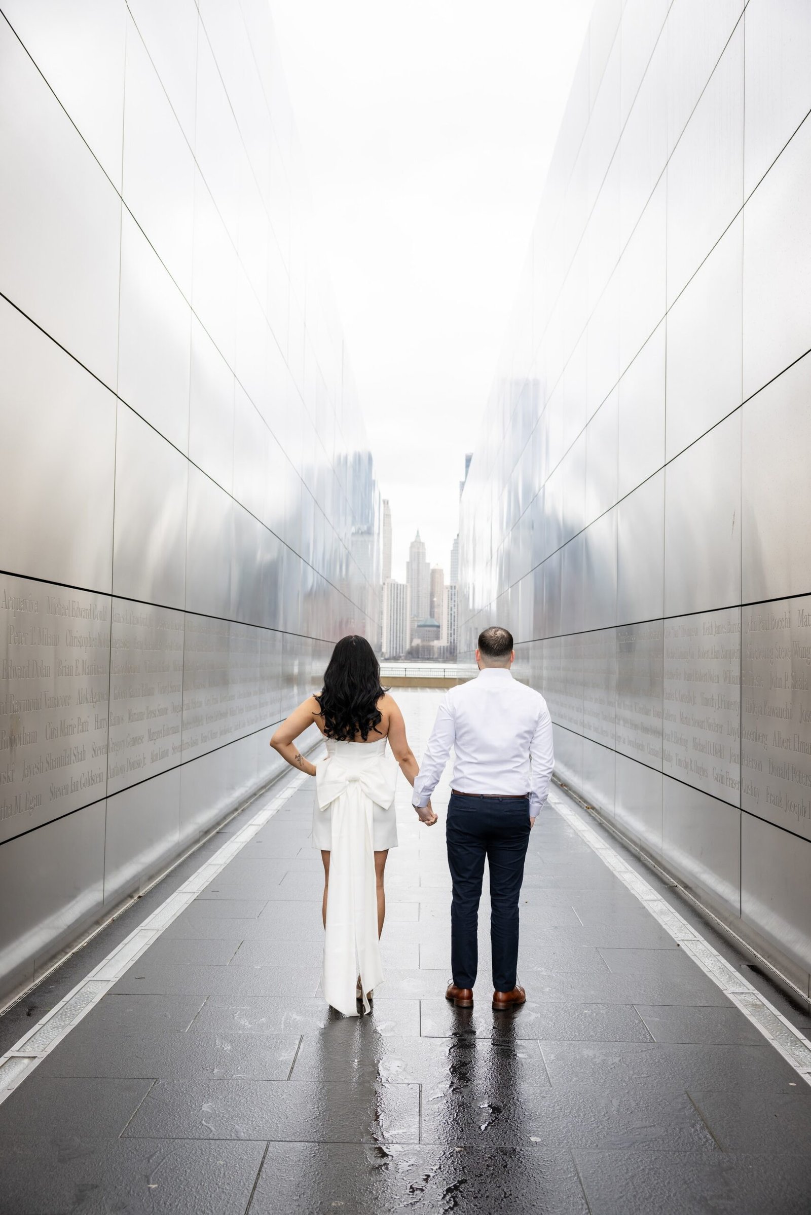 Black and white photograph of the couple walking hand in hand through the Empty Sky Memorial