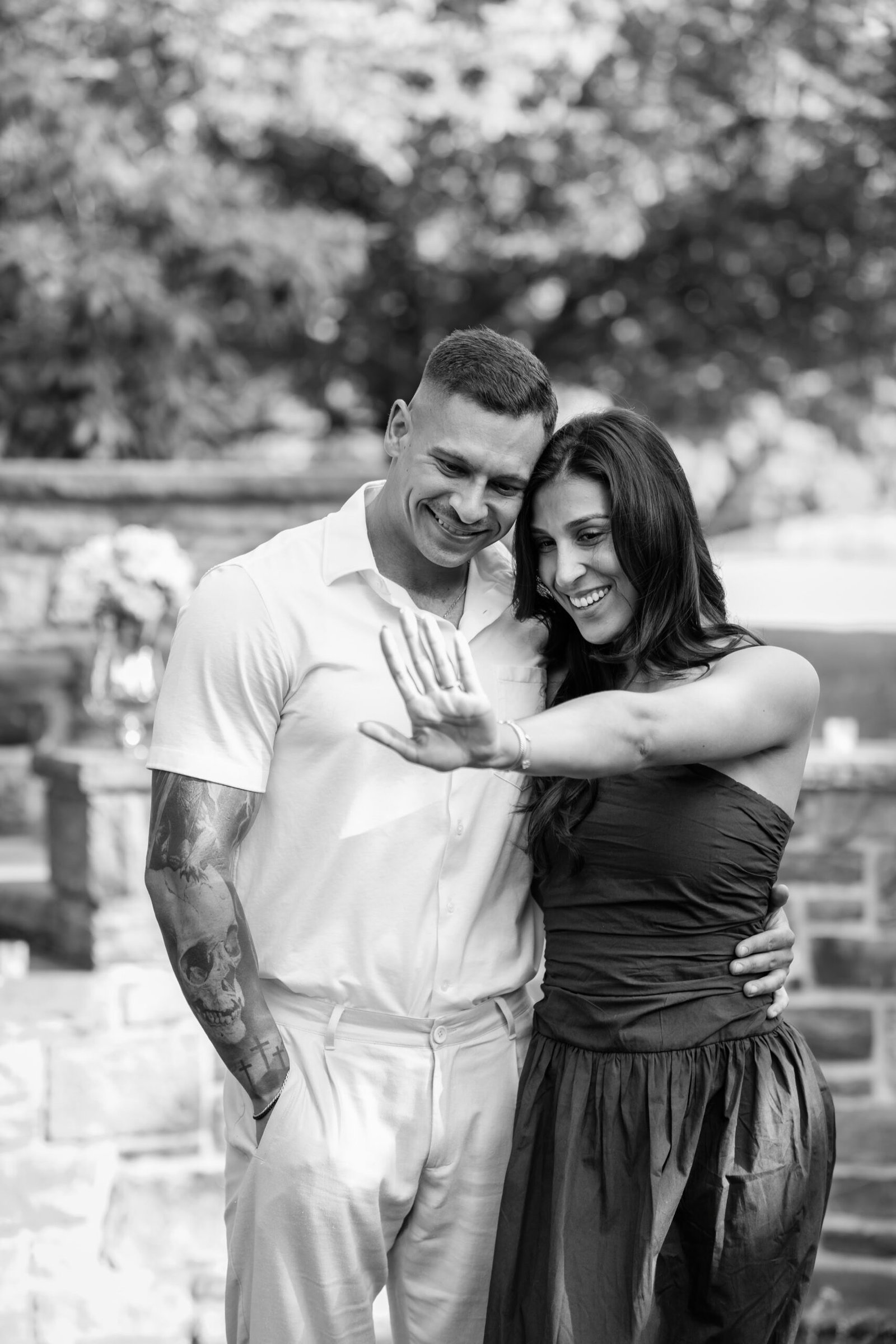 Black and white photograph of the couple showing the engagement ring after saying yes