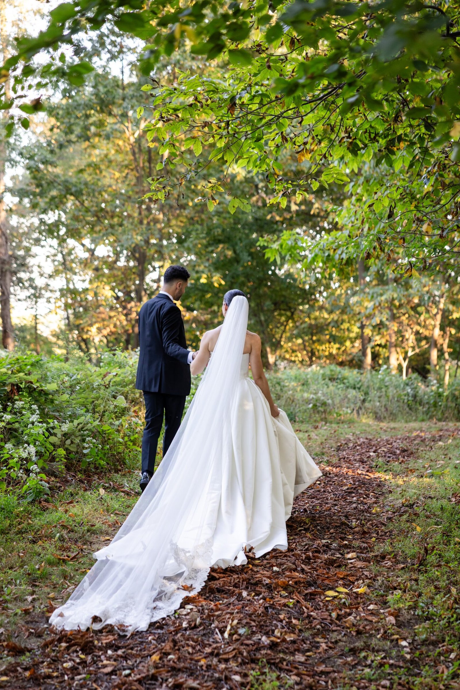 Bride walking through the gardens with her veil trailing