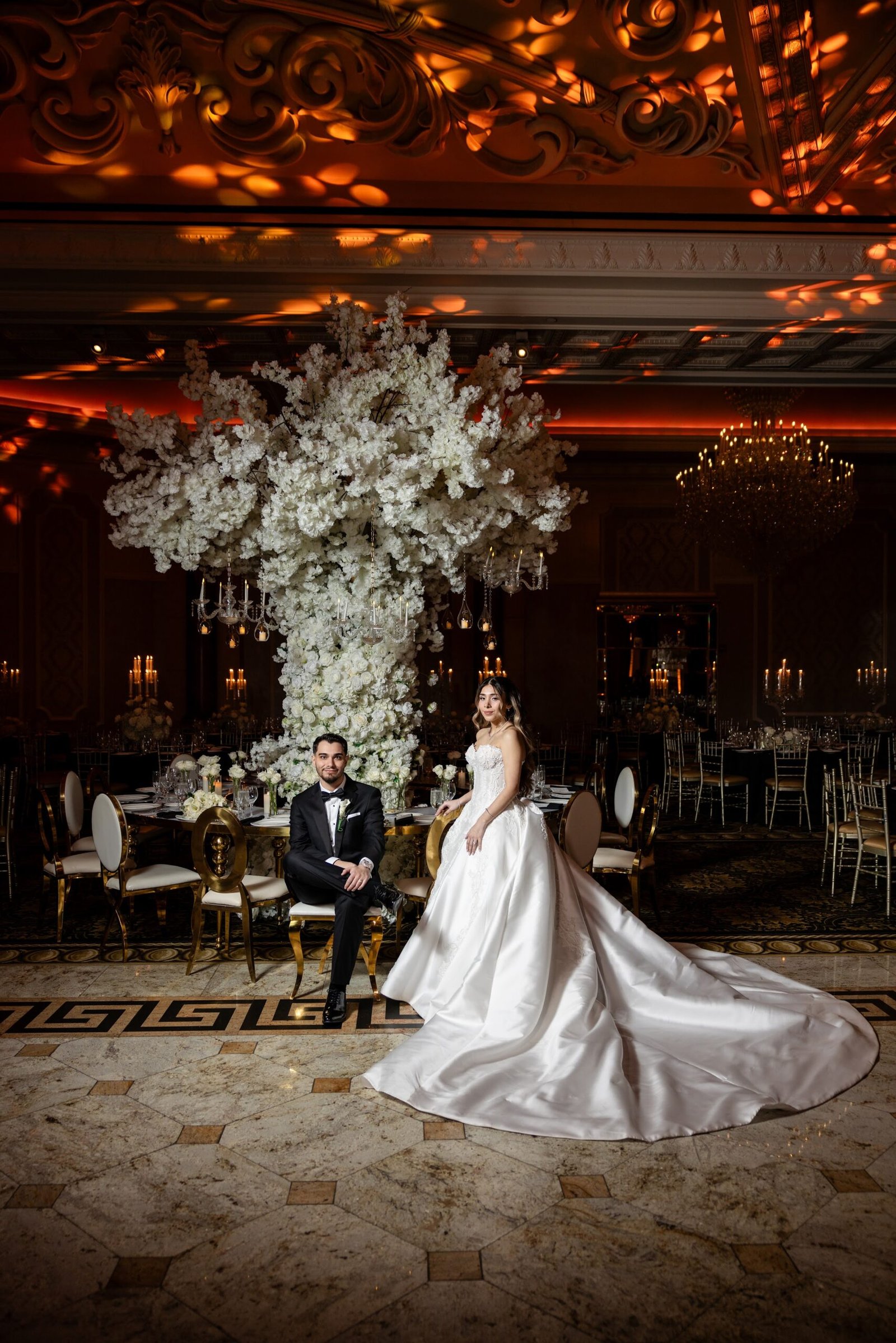 Bride seated in the ballroom surrounded by white florals